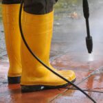 persona vestida botas goma amarilla boquilla agua alta presion limpiando suciedad baldosas